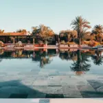 a swimming pool with a tiled floor next to palm trees